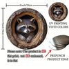 A round aluminum wall art sign featuring a raccoon peering out of a tree hole design.