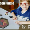 A young boy is looking at a wooden puzzle piece on a table, with various puzzle pieces visible nearby.