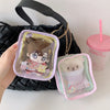 A pink storage pouch with a keychain featuring a cute doll inside, displayed next to a pink drink cup.