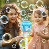 Two children are blowing bubbles outdoors near an automatic bubble machine with lights and music.