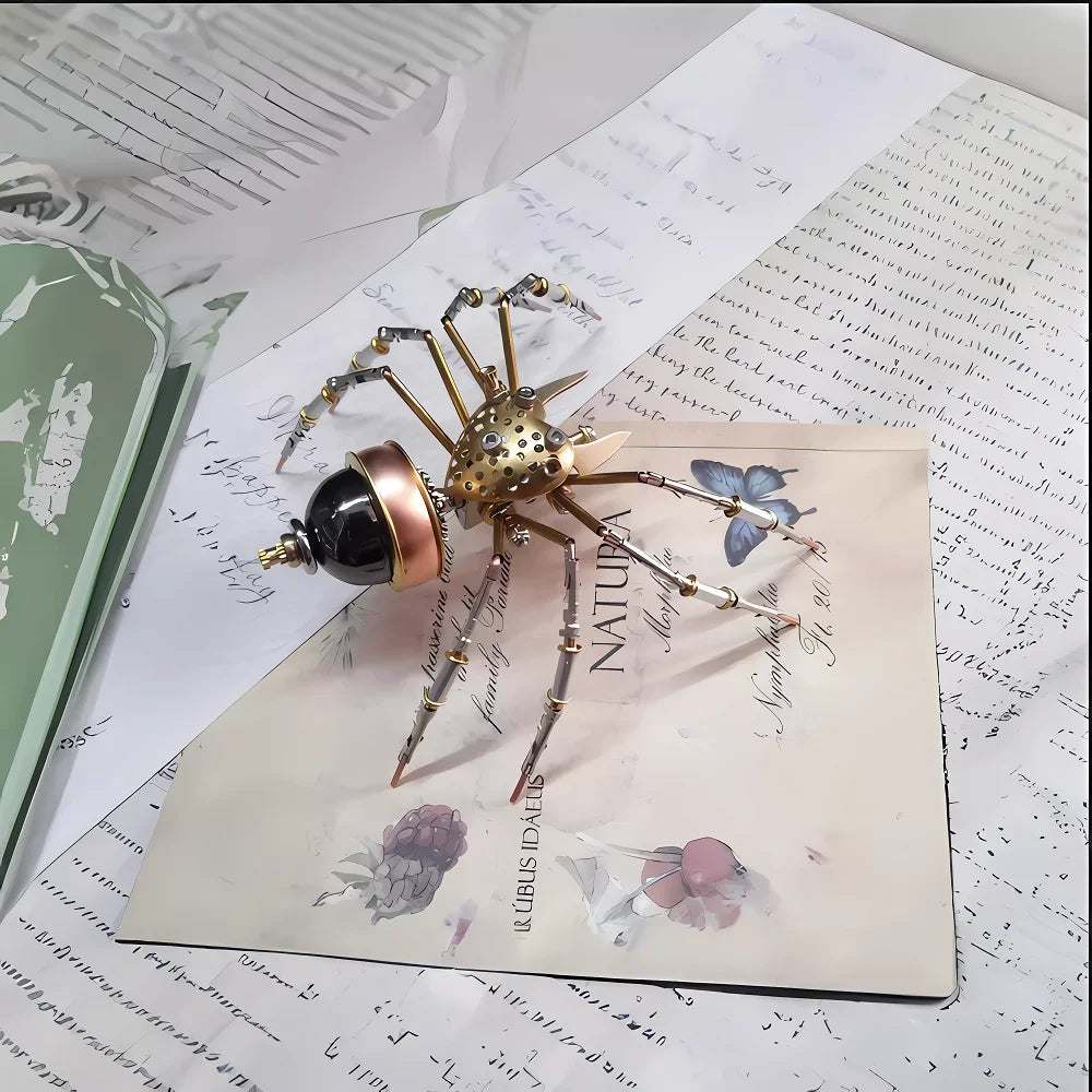 A detailed steampunk metal spider model is displayed on a light-colored paper next to writing paper.