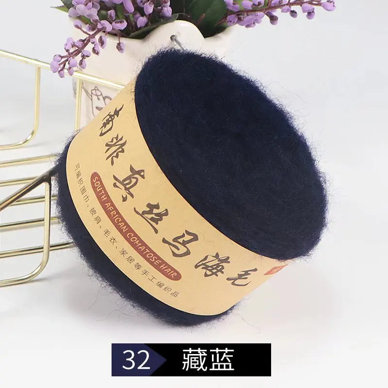 A dark navy blue yarn ball labeled South African Cohoose Hair used for knitting shawls and sweaters.