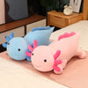 A soft, large plush toy of a blue and pink axolotl is lying on a light pink mat.