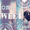 A wooden background with text reading Home Sweet Home and New Home, featuring a heart-shaped key.