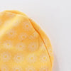 A close-up of a yellow baby hat with a white sunburst pattern.