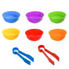 A set of colorful plastic bowls in blue, purple, green, yellow, and red, along with tweezers for a sorting and counting toy s