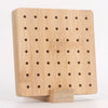 A light wood bamboo crochet blocking board with numerous holes and a stand.