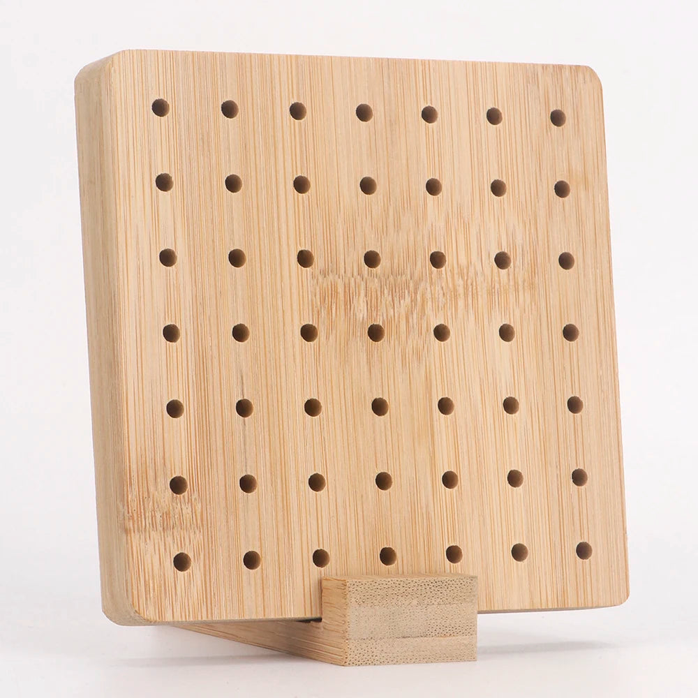 A light wood bamboo crochet blocking board with numerous holes and a stand.