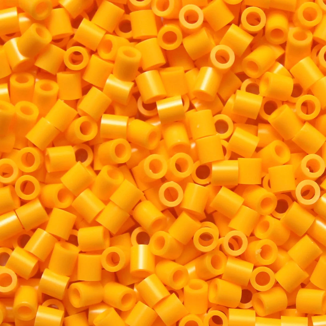 A pile of bright orange and yellow creative fuse beads for a craft kit.