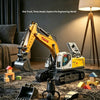 A yellow remote control excavator toy with interchangeable attachments resting on a dark rug.