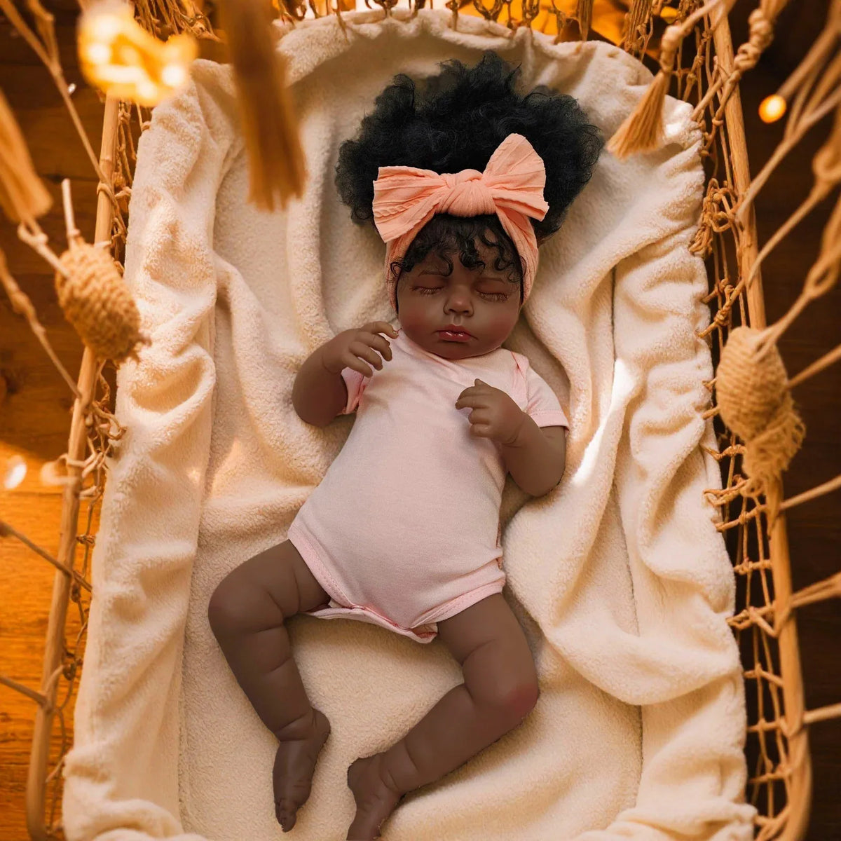 A lifelike 19-inch reborn baby doll with hand-rooted hair lying in a cream-colored fabric nest.