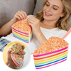 A woman holds a rainbow layer cake squishy toy with colorful frosting and stripes.
