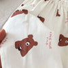 Close-up of white casual pants featuring brown bear print details and elastic waistline.