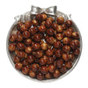 A pile of round, reddish-brown resin beads for jewelry making displayed in a silver dish with a bow.