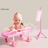 A pink baby doctor toy set featuring a baby figure, a pink stretcher, and a syringe on a stand.