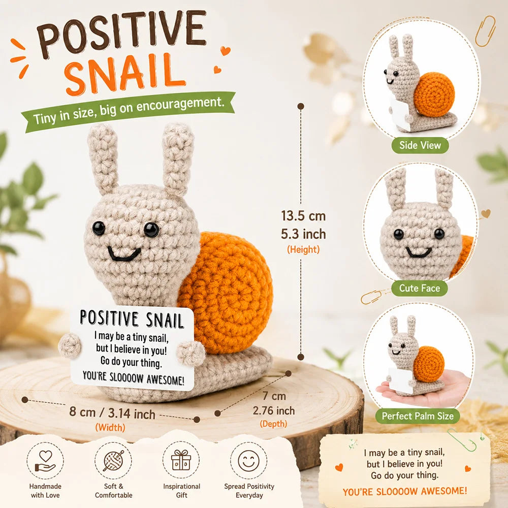 A handmade crochet positive snail toy in light gray and orange with a motivational card.