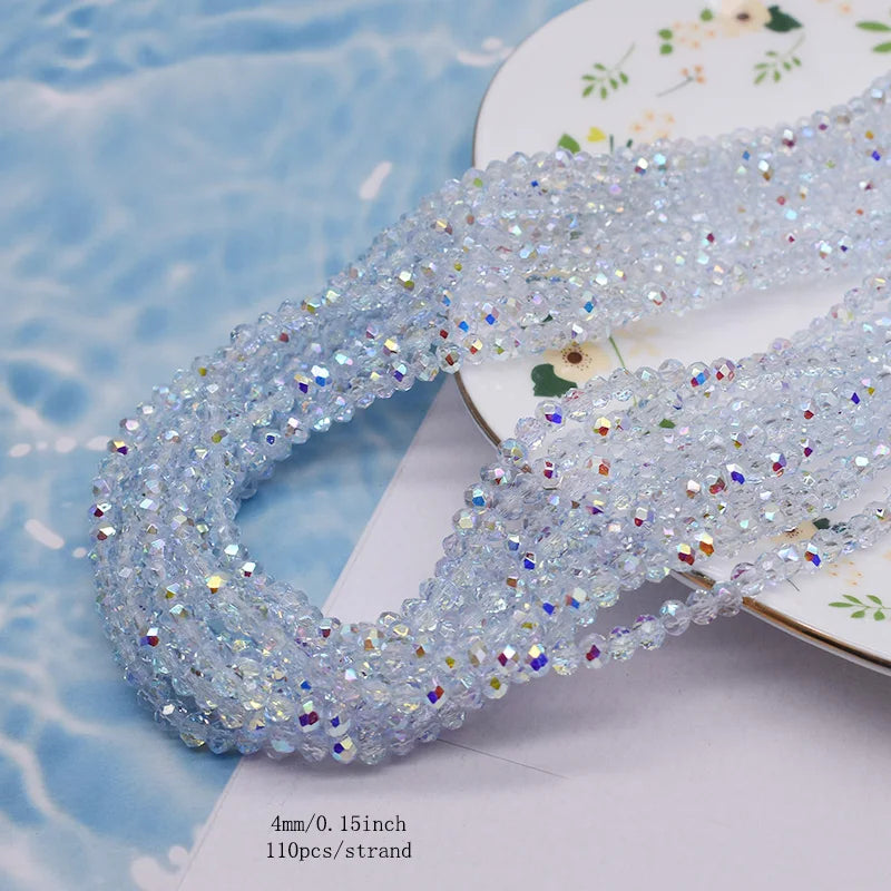 A strand of clear faceted crystal rondelle beads for jewelry making laid on a white surface.