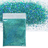 A small white bag filled with vibrant teal holographic glitter powder next to a loose pile of the same glitter.