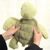 A person is holding a soft, light green simulated turtle plush doll.