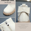 A pair of light beige faux leather winter boots with a decorative bow detail and zipper closure.