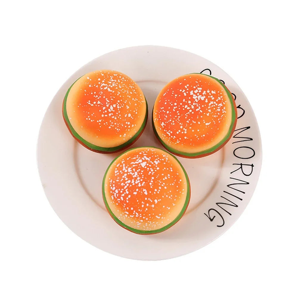 A bright orange squishy hamburger stress ball with white sprinkles is displayed on a white plate.