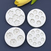A set of white silicone daisy flower molds for fondant and cake decorating, with a yellow flower petal visible in the backgro
