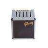 A gray guitar pick holder with a speaker-shaped design and gold-colored tuning pegs.