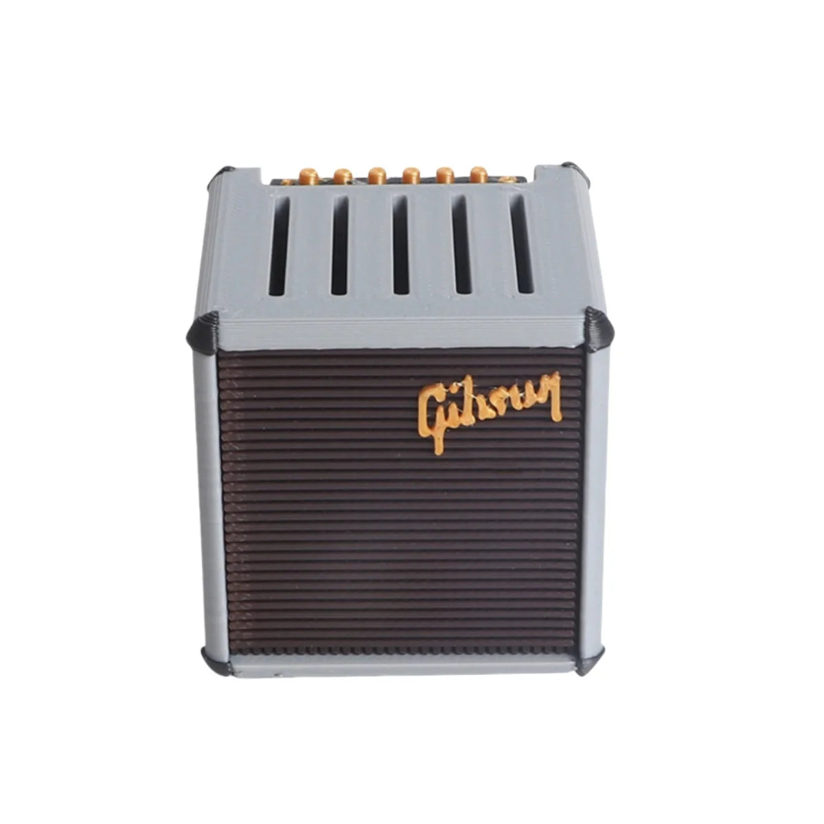 A gray guitar pick holder with a speaker-shaped design and gold-colored tuning pegs.