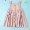 A pink linen jumper dress for a toddler girl with buttons, displayed against a light blue background.