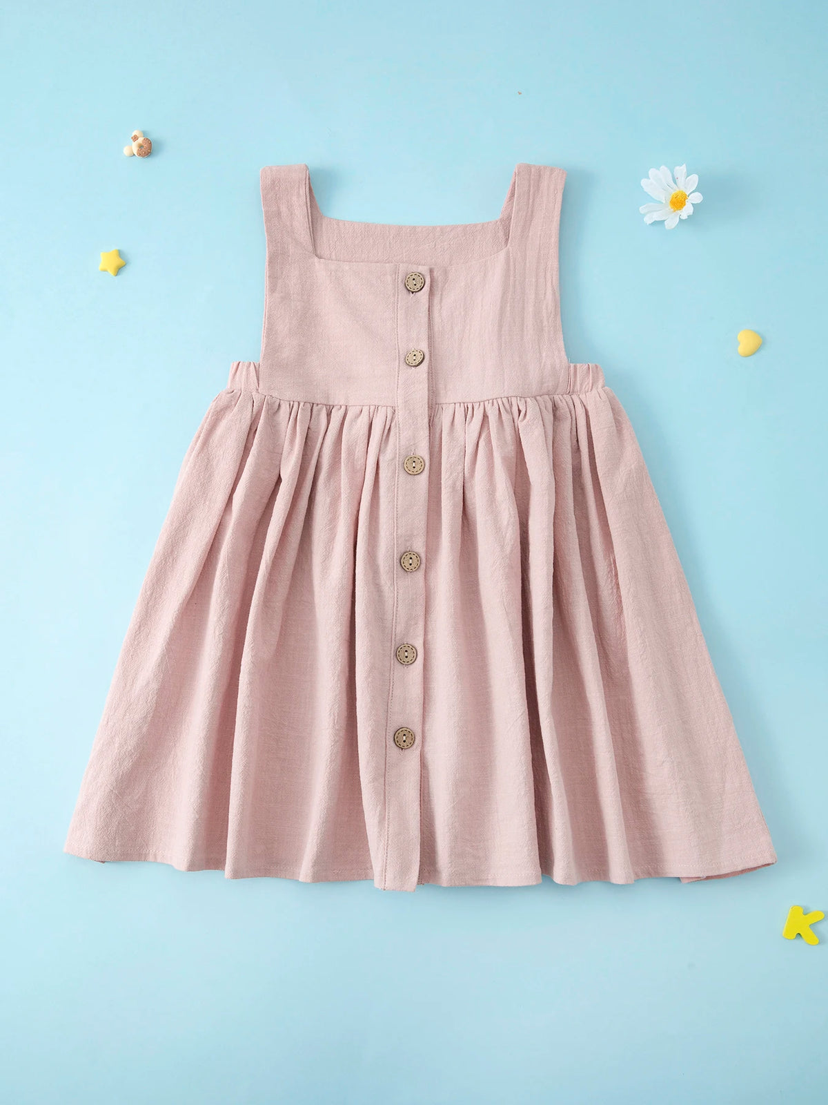 A pink linen jumper dress for a toddler girl with buttons, displayed against a light blue background.