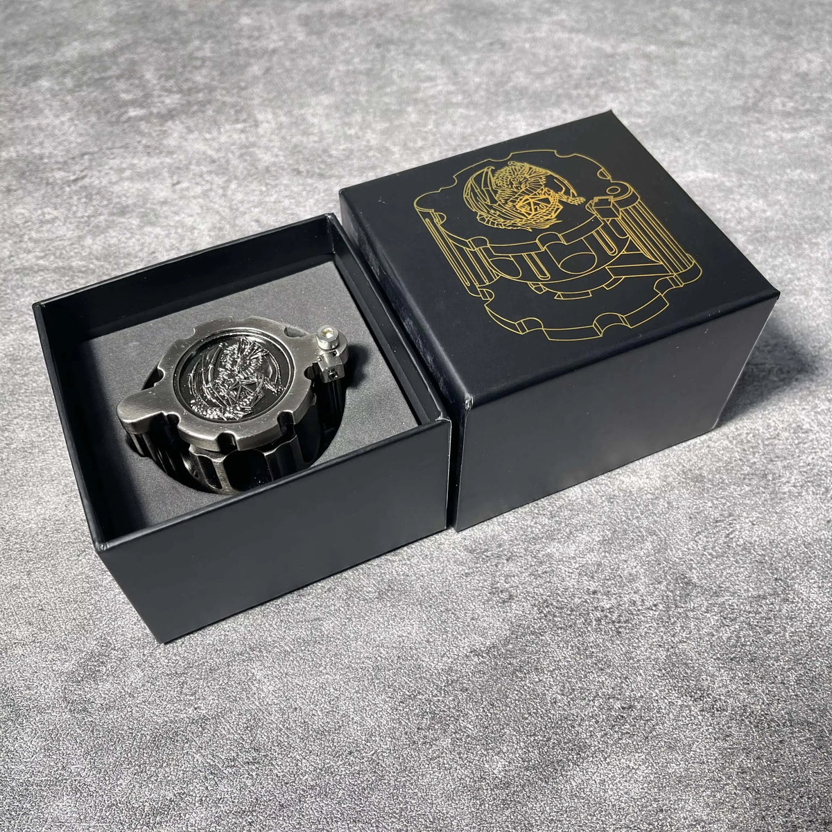 Una caja negra que contiene un juego de dados poliedrales de metal con un emblema de color dorado en la tapa.