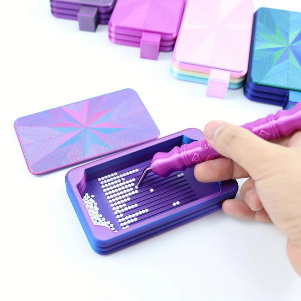 A hand is using a purple diamond painting tray to place small white beads onto a canvas.