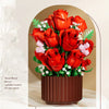 A bouquet of red roses and white filler flowers in a brown planter.