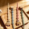 A set of baby pacifier clips featuring burlap flower designs in pastel colors on a wooden tray.