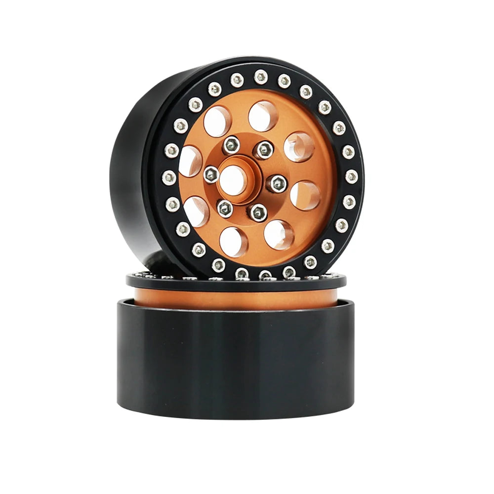 A close-up view of a black beadlock wheel with an orange center and removable hex hub.