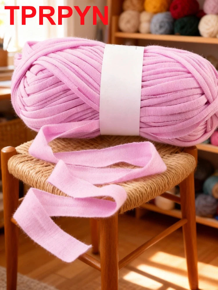 A pink ball of soft chunky t-shirt yarn is displayed on a wooden stool.