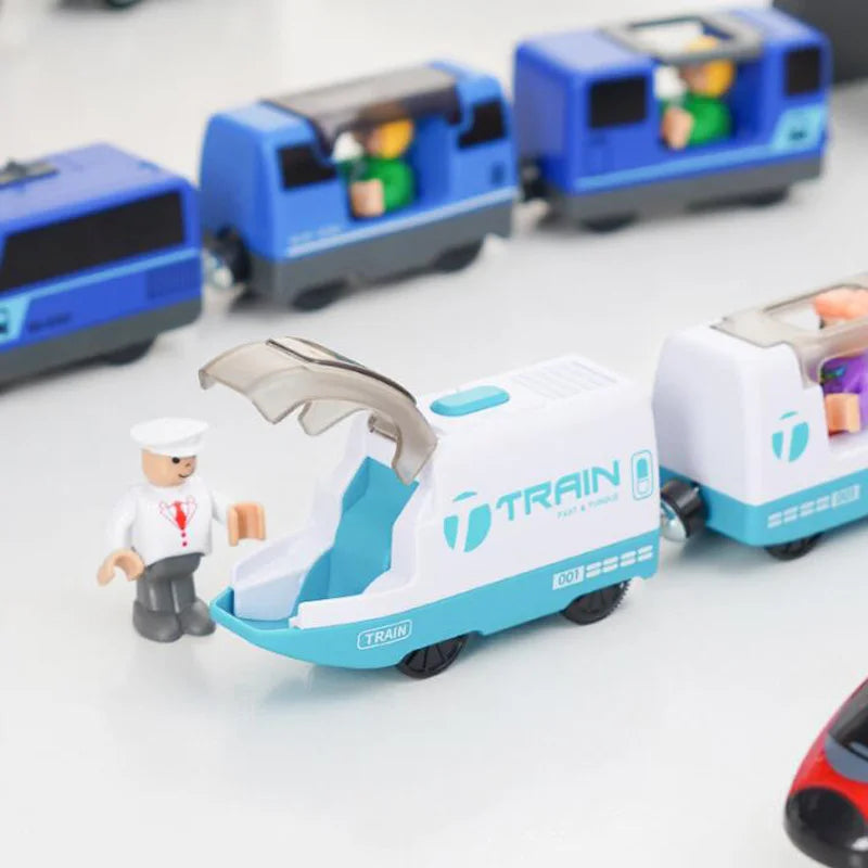 A white and teal battery-powered magnetic wooden train set with a transparent engine piece and a figure on the track.