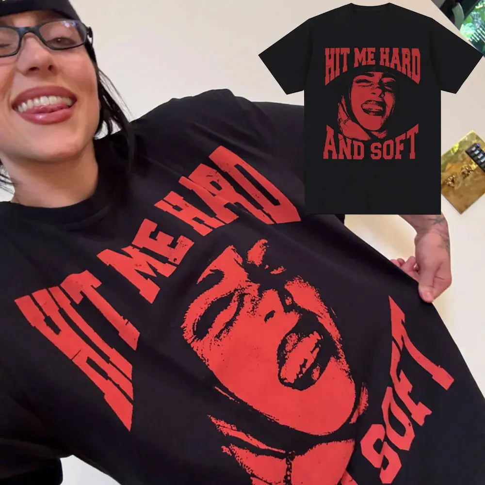 A woman wearing a black t-shirt featuring the text Hit Me Hard and Soft in red print.