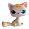 A pink and white cat bobble head figurine with large green eyes and orange spots.