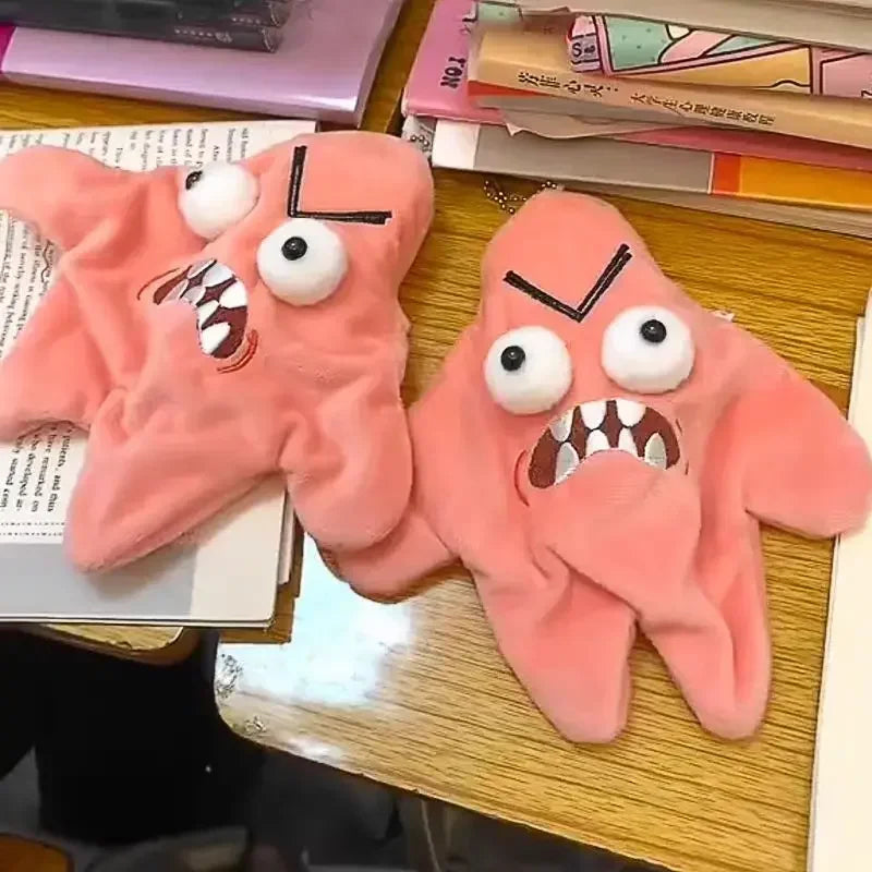 A pair of pink plush hand charms with exaggerated, angry facial expressions.