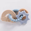 A set of silicone teether rings shaped like a rainbow, cloud, and star, in beige, blue, and natural wood tones.