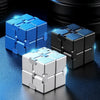 Un ensemble de cubes anti-stress à l'infini en métal bleu, noir et argent reposant sur une surface sombre.