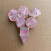 A set of seven pink glitter polyhedral dice, including a d4, d6, d8, d10, d12, and d20.