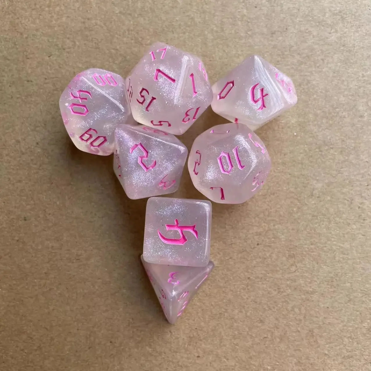 A set of seven pink glitter polyhedral dice, including a d4, d6, d8, d10, d12, and d20.
