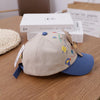 A beige toddler baseball cap with a blue brim and an adjustable strap, featuring colorful bear graphics.