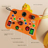 An orange Montessori busy board with various LED light switches and levers, shown being operated by a hand.