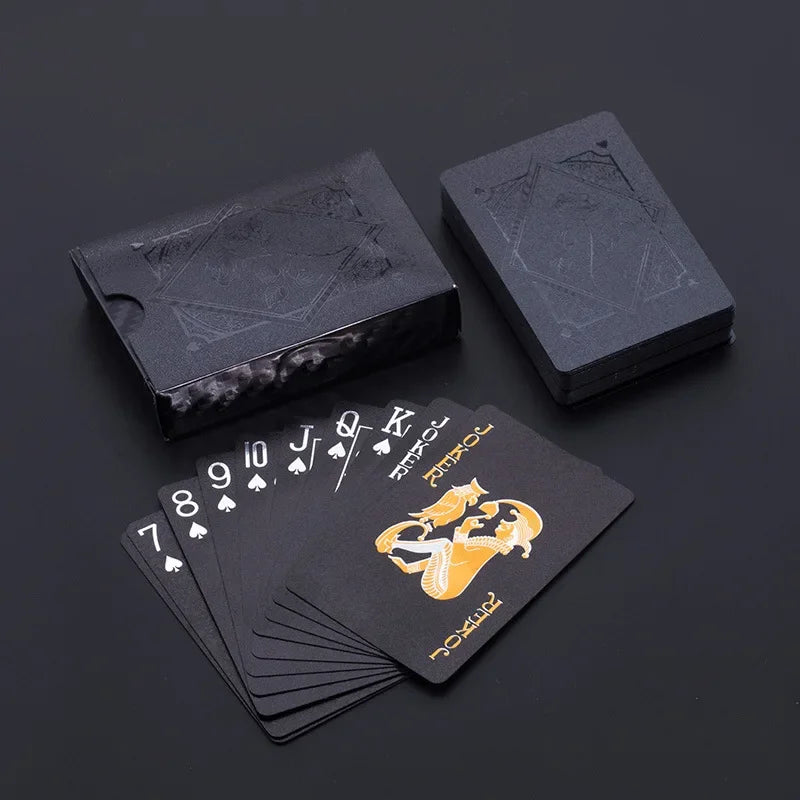 A stack of elegant black and gold waterproof playing cards next to a dark rectangular box.