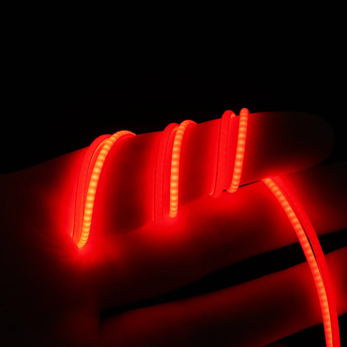 A close-up of flexible LED strip lights illuminating a hand, showing the light tracing the contours of the skin.