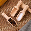 A set of three natural wooden scoop spoons resting on a woven bamboo mat.