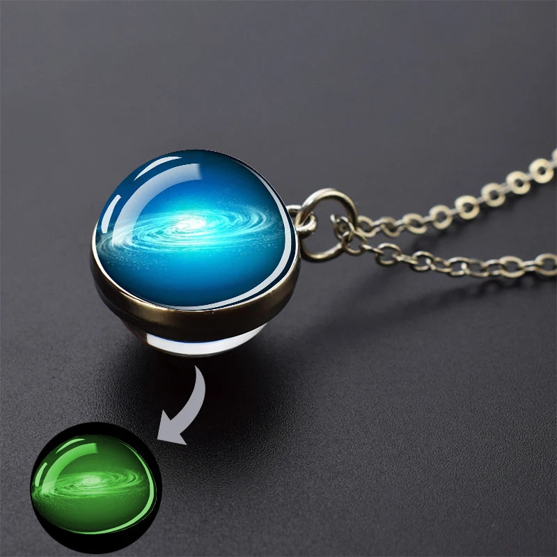 A pendant necklace featuring a blue, swirling galaxy charm and a green glow-in-the-dark sphere.